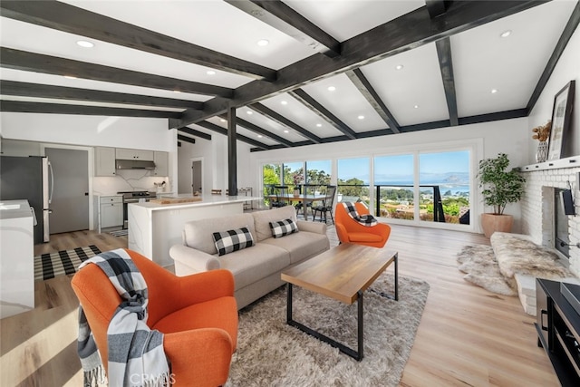 living room featuring a brick fireplace, lofted ceiling with beams, light hardwood / wood-style floors, and a wealth of natural light