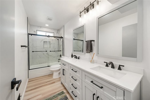 full bathroom featuring shower / bath combination with glass door, vanity, toilet, and hardwood / wood-style flooring