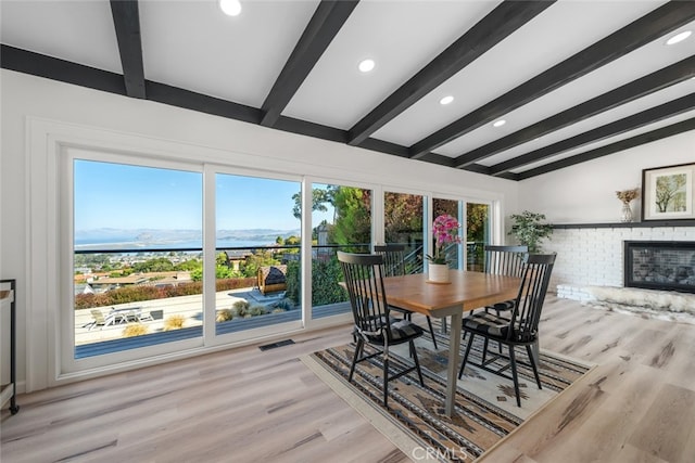 dining room featuring light hardwood / wood-style floors, a brick fireplace, and a wealth of natural light