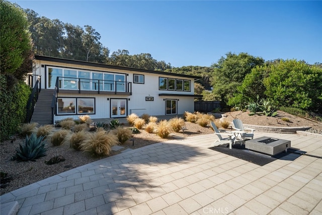 rear view of house with a fire pit and a patio