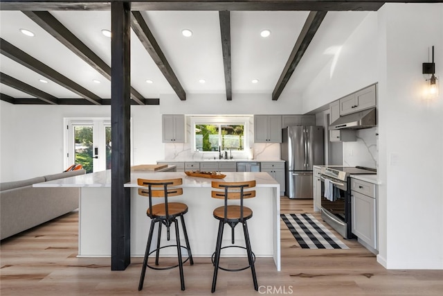 kitchen with a kitchen breakfast bar, a healthy amount of sunlight, stainless steel appliances, and gray cabinets