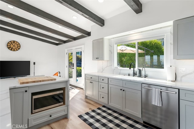 kitchen with gray cabinetry, beamed ceiling, appliances with stainless steel finishes, and tasteful backsplash