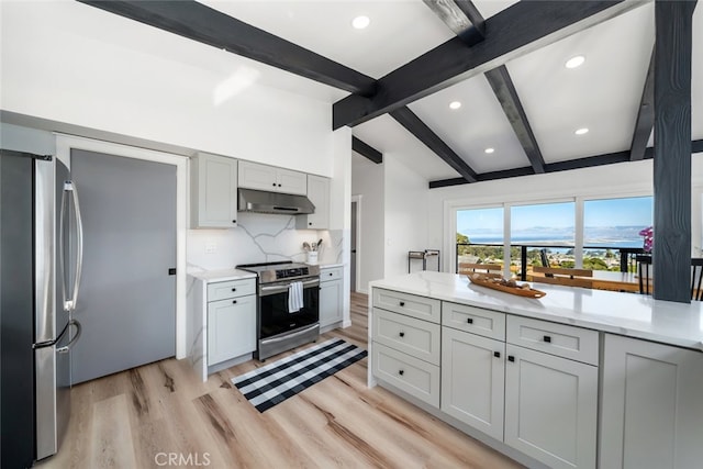 kitchen with vaulted ceiling with beams, light stone countertops, tasteful backsplash, appliances with stainless steel finishes, and light wood-type flooring