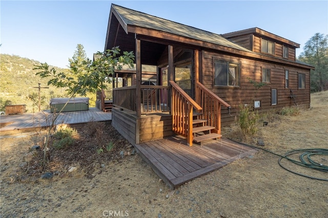 back of house with a hot tub and a deck