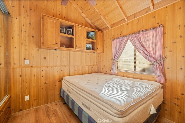 bedroom with lofted ceiling with beams, light hardwood / wood-style floors, wooden ceiling, and wood walls