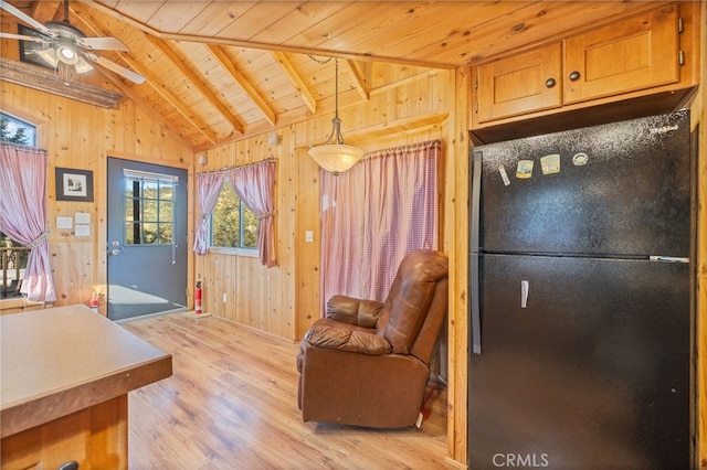 interior space featuring ceiling fan, wood walls, lofted ceiling with beams, wooden ceiling, and light wood-type flooring