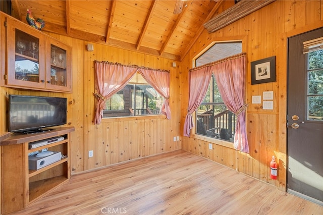 living room with light hardwood / wood-style flooring, wood ceiling, vaulted ceiling with beams, and wood walls