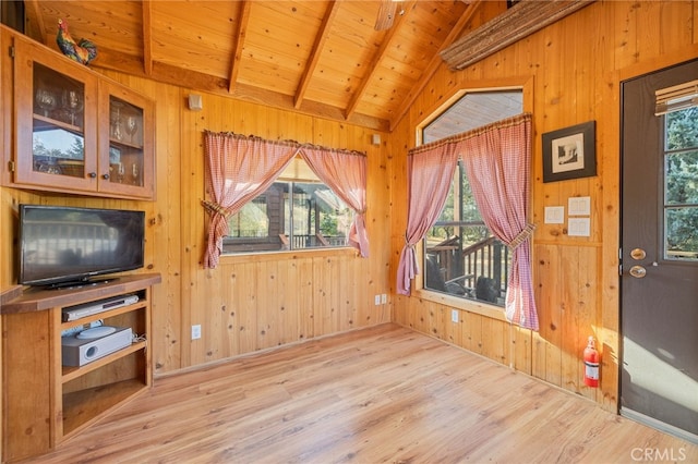 living room with a healthy amount of sunlight, light hardwood / wood-style flooring, lofted ceiling with beams, and wooden ceiling