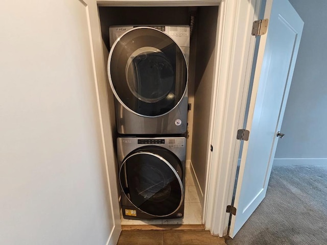 laundry area with stacked washing maching and dryer and dark colored carpet