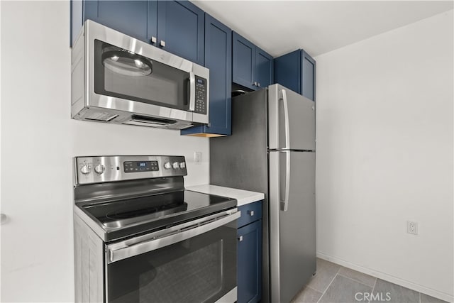 kitchen with blue cabinets, light tile patterned flooring, and stainless steel appliances