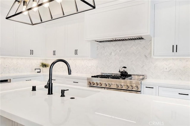 details with high end range, white cabinetry, sink, and tasteful backsplash