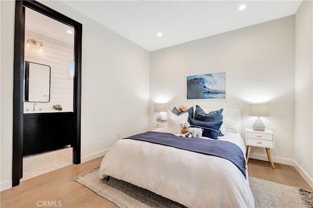 bedroom with light hardwood / wood-style floors and ensuite bath