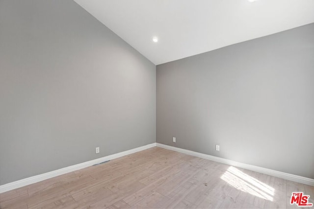 empty room with light hardwood / wood-style floors and lofted ceiling