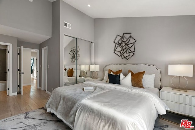 bedroom with high vaulted ceiling, light hardwood / wood-style flooring, and a closet