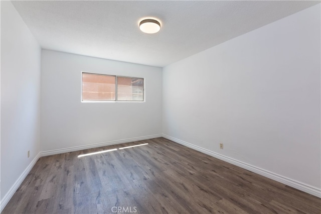 empty room featuring a textured ceiling and dark wood-type flooring