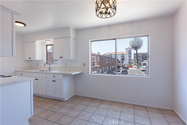 kitchen with a chandelier, light tile patterned floors, white cabinetry, and sink