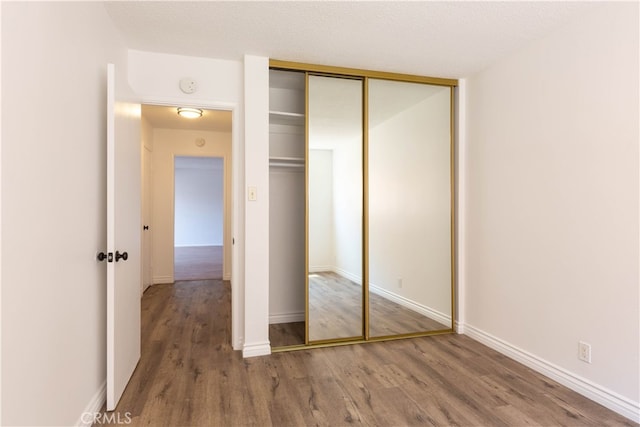 unfurnished bedroom with hardwood / wood-style floors, a textured ceiling, and a closet