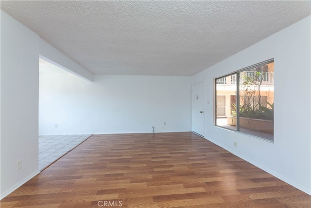 empty room with dark hardwood / wood-style flooring and a textured ceiling