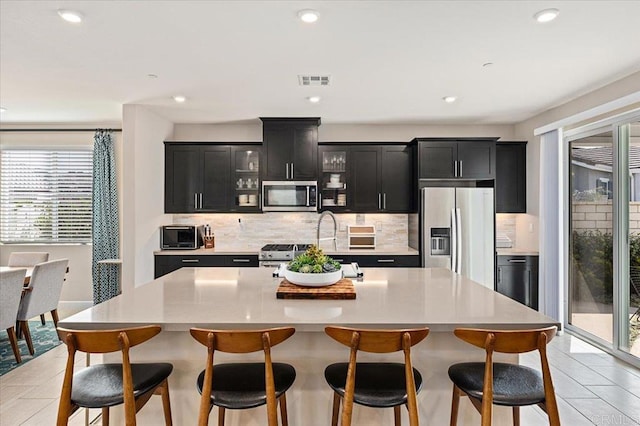 kitchen featuring a kitchen breakfast bar, appliances with stainless steel finishes, decorative backsplash, and a large island