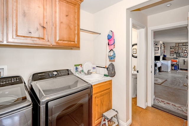 washroom with cabinets, sink, and washing machine and dryer