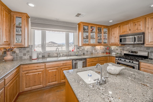 kitchen with a mountain view, tasteful backsplash, sink, stainless steel appliances, and light stone countertops