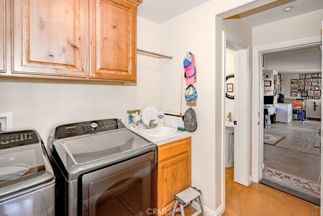 washroom featuring cabinets, independent washer and dryer, and sink