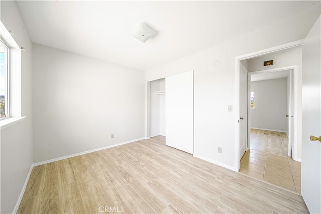 unfurnished bedroom with a closet and light hardwood / wood-style floors