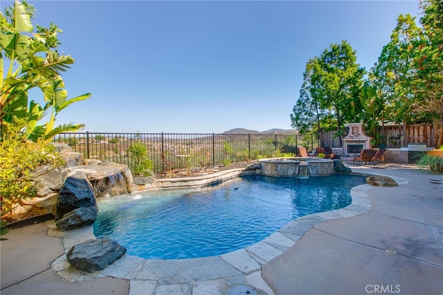 view of pool with pool water feature, an outdoor fireplace, a mountain view, and a patio