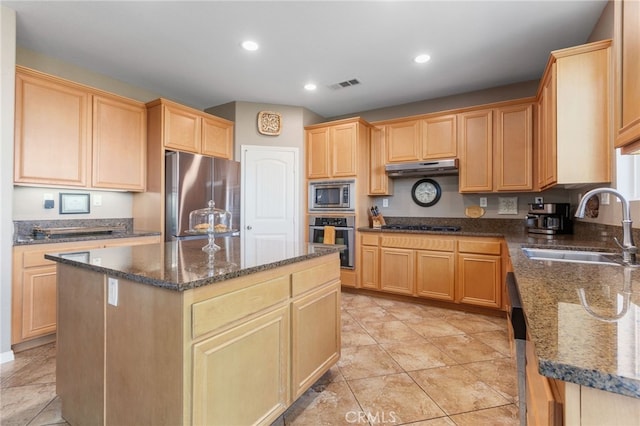 kitchen featuring light tile patterned floors, stainless steel appliances, a center island, dark stone countertops, and sink