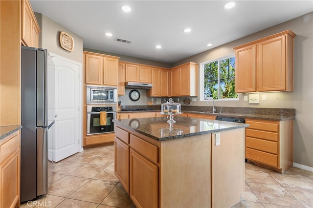 kitchen with a center island, stainless steel appliances, dark stone countertops, sink, and light tile patterned flooring