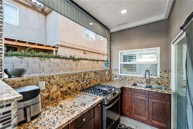 kitchen with light stone counters, plenty of natural light, sink, and gas stove