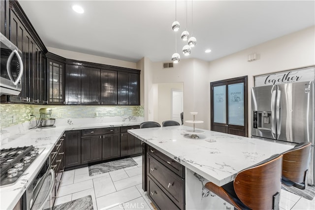 kitchen featuring decorative backsplash, a center island, a breakfast bar, pendant lighting, and appliances with stainless steel finishes