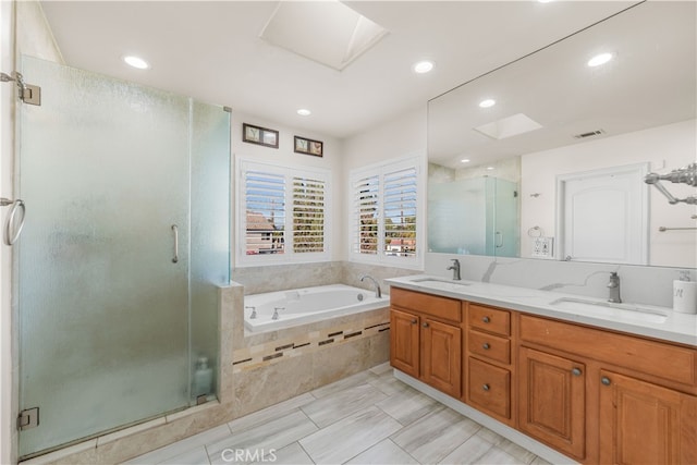 bathroom with plus walk in shower, a skylight, and vanity