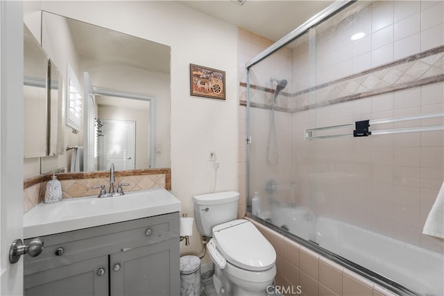 full bathroom with enclosed tub / shower combo, vanity, and toilet