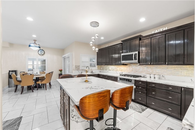 kitchen featuring a kitchen island, tasteful backsplash, a breakfast bar, hanging light fixtures, and appliances with stainless steel finishes