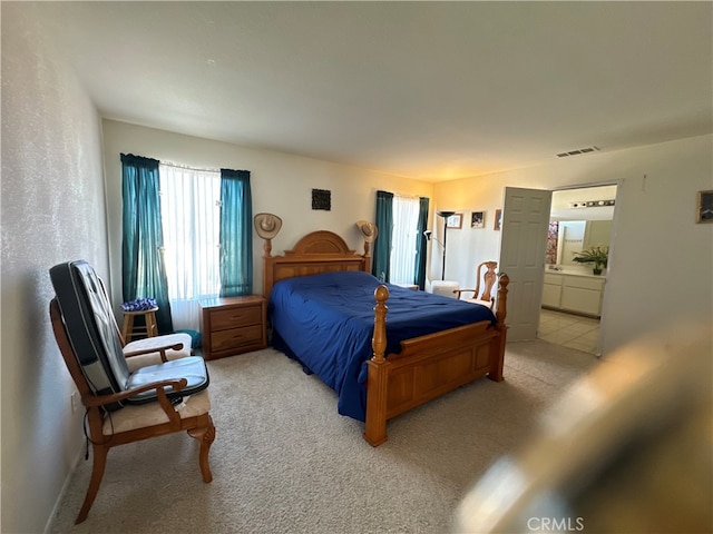 bedroom with light colored carpet and connected bathroom