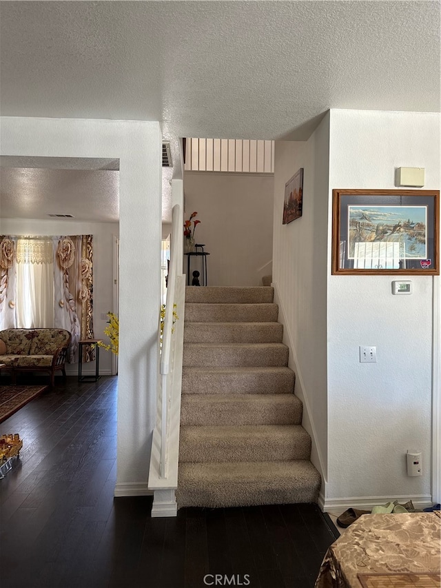 stairway featuring hardwood / wood-style floors and a textured ceiling