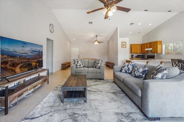 tiled living room with ceiling fan and high vaulted ceiling