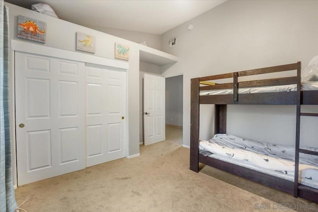 unfurnished bedroom with vaulted ceiling, a closet, and light colored carpet