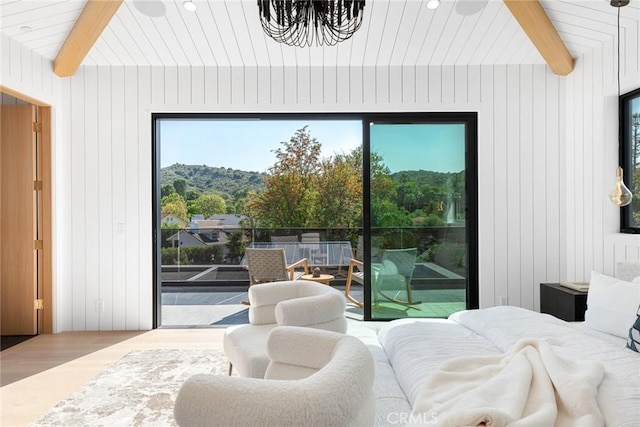 bedroom with hardwood / wood-style floors, vaulted ceiling with beams, wood walls, and access to exterior