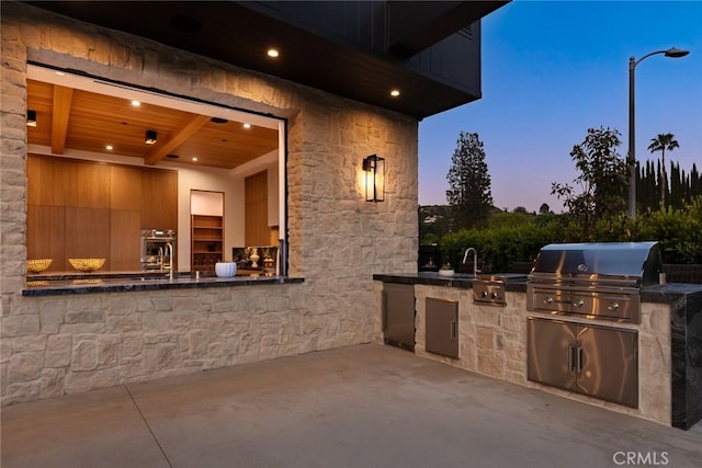 patio terrace at dusk featuring grilling area, sink, and area for grilling