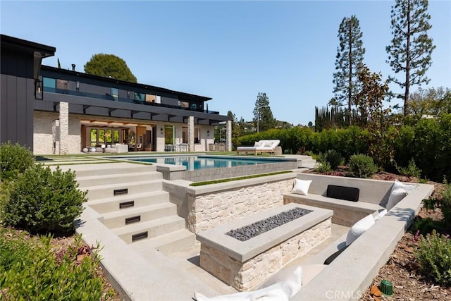 view of pool featuring a patio area and an outdoor living space with a fire pit