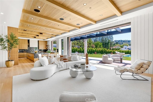 living room featuring beamed ceiling, wooden ceiling, light hardwood / wood-style flooring, and a healthy amount of sunlight