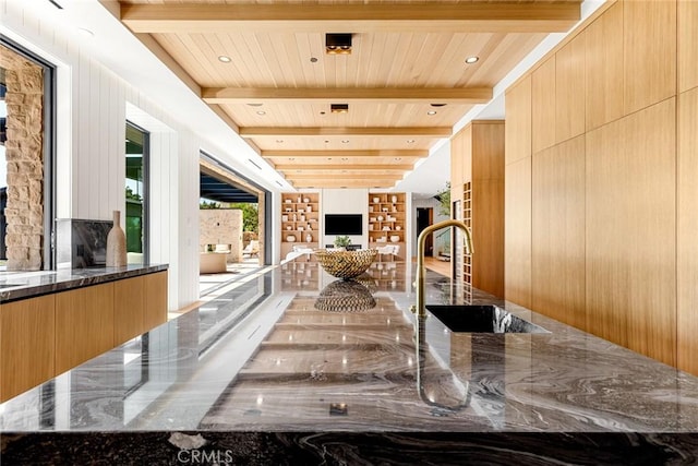 kitchen featuring beam ceiling, sink, and dark stone countertops