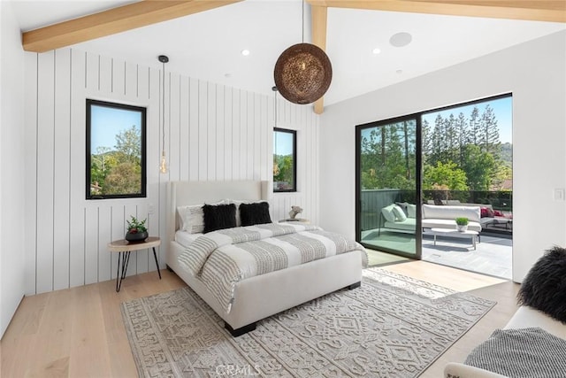 bedroom featuring access to exterior, vaulted ceiling with beams, light hardwood / wood-style flooring, and multiple windows