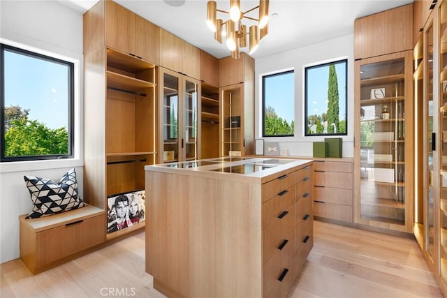 walk in closet with light wood-type flooring and a chandelier