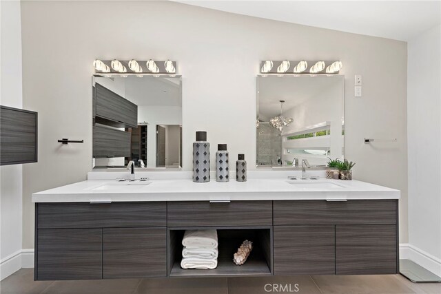 bathroom with vanity, vaulted ceiling, a notable chandelier, and tile patterned flooring