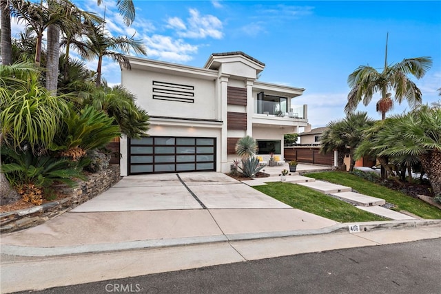 view of front facade featuring a garage, concrete driveway, a balcony, and stucco siding