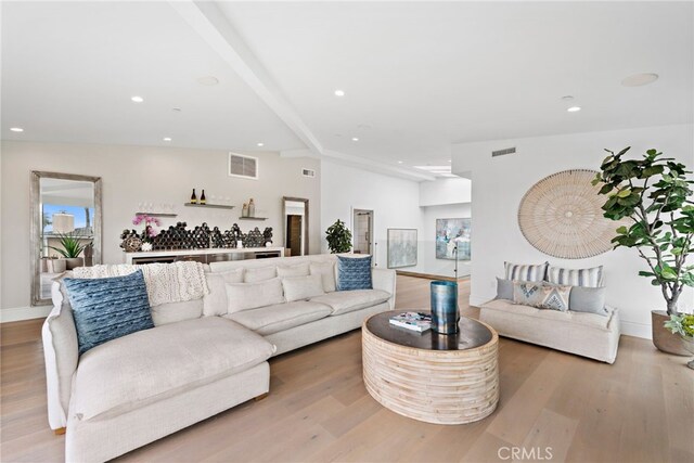 living room with light hardwood / wood-style floors and lofted ceiling with beams