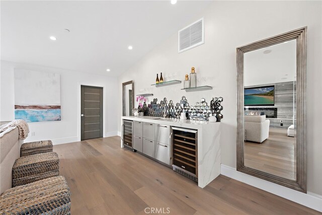 bar featuring wine cooler, vaulted ceiling, and wood-type flooring